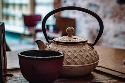 Free Vintage pottery teapot and cup setting in a cozy indoor environment. Stock Photo