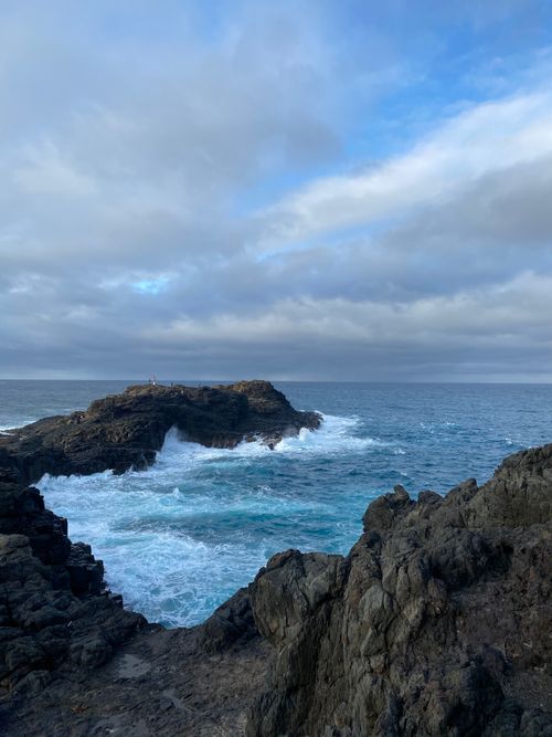 Free Powerful waves crash against rocky formations under a cloudy sky. Stock Photo