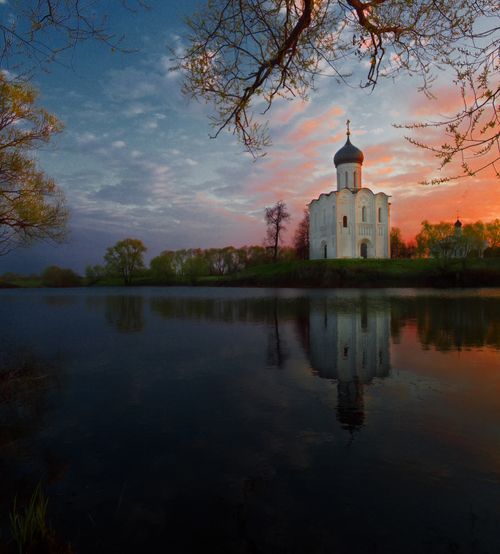 Free Beautiful sunrise view of the Church of the Intercession on the Nerl reflecting in a tranquil lake in Bogolyubovo, Russia. Stock Photo
