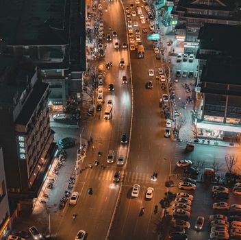 Aerial view of a busy urban street at night with traffic and buildings.