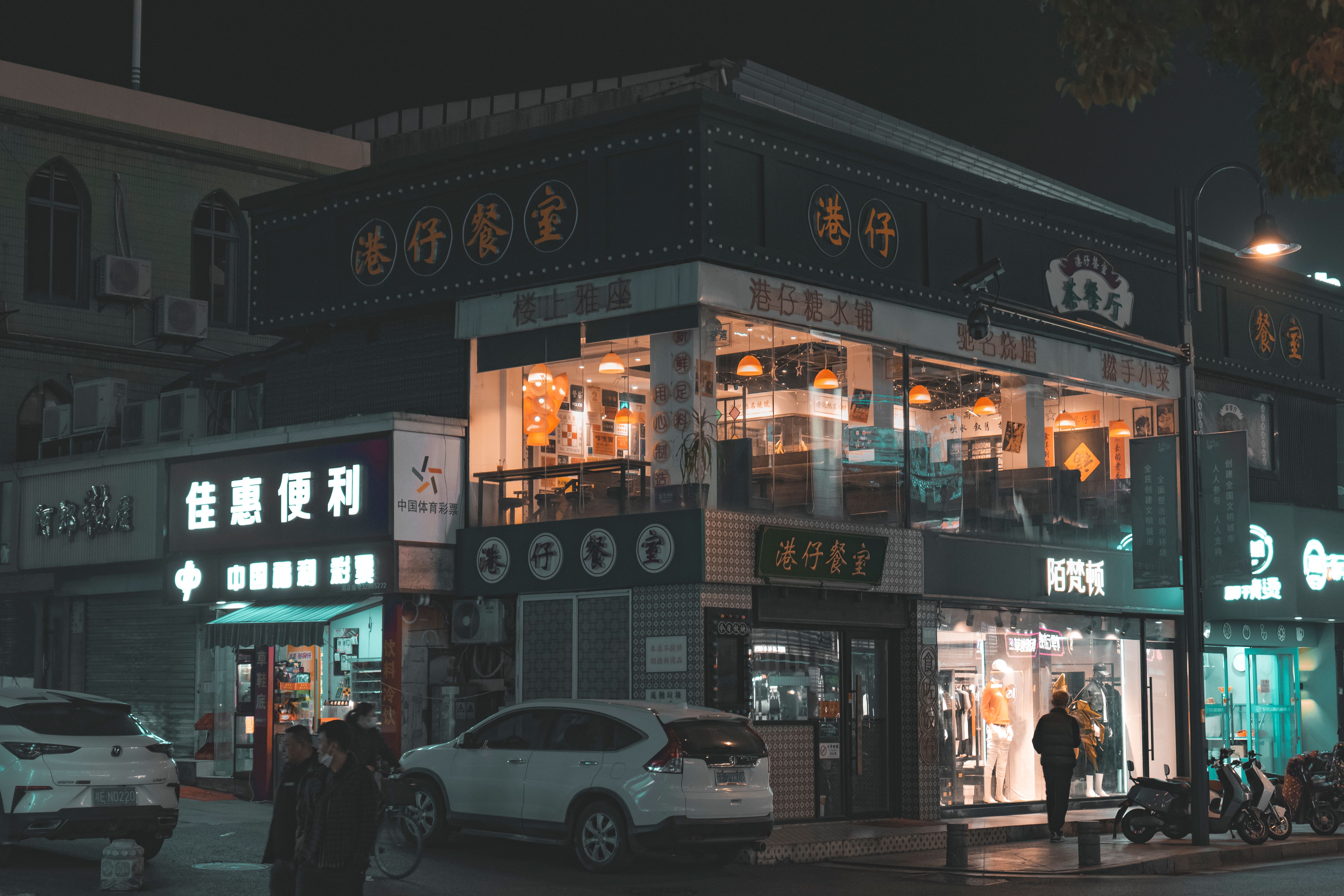 Illuminated shopfronts along a busy street at night — the F&B podium is where the population is generated