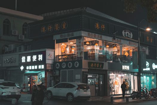 Illuminated shopfronts and streets in a bustling Asian city at night.