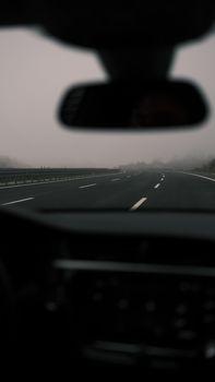 Misty highway scene as viewed from inside a car, emphasizing calmness and solitude.