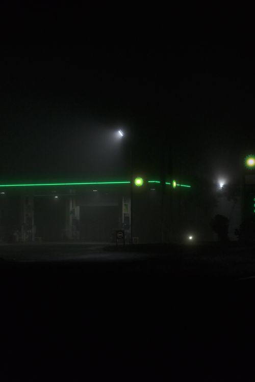 Free Illuminated gas station glowing in the fog during nighttime, creating a moody and mysterious atmosphere. Stock Photo