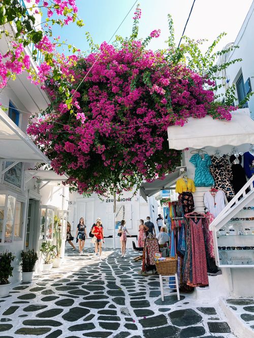 Free Explore the colorful, vibrant streets of Mikonos town with blooming bougainvillea and local shops. Stock Photo