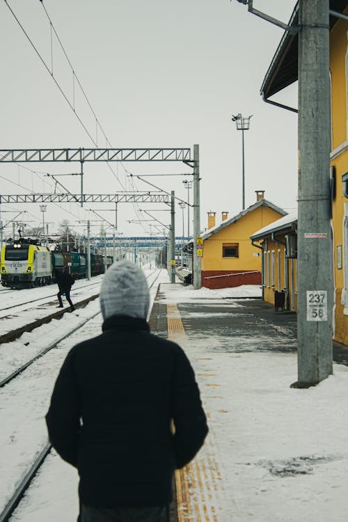 Backview of Person in Black Hoodie standing beside a Railway 