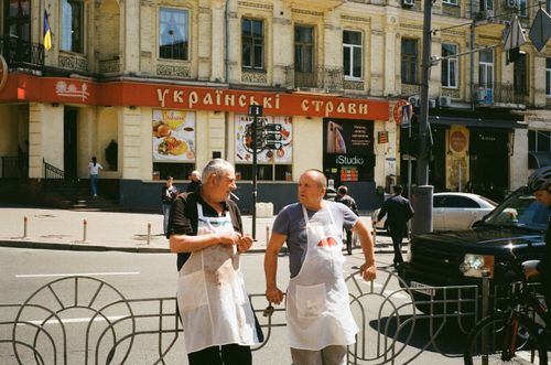 Free Two chefs in aprons converse on a busy city street, highlighting urban life. Stock Photo