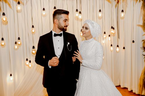 Free An elegant indoor wedding portrait of a newlywed couple posing with vintage lighting decor. Stock Photo