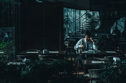 一个男人独自在灯光昏暗的咖啡馆里读书，显得十分宁静