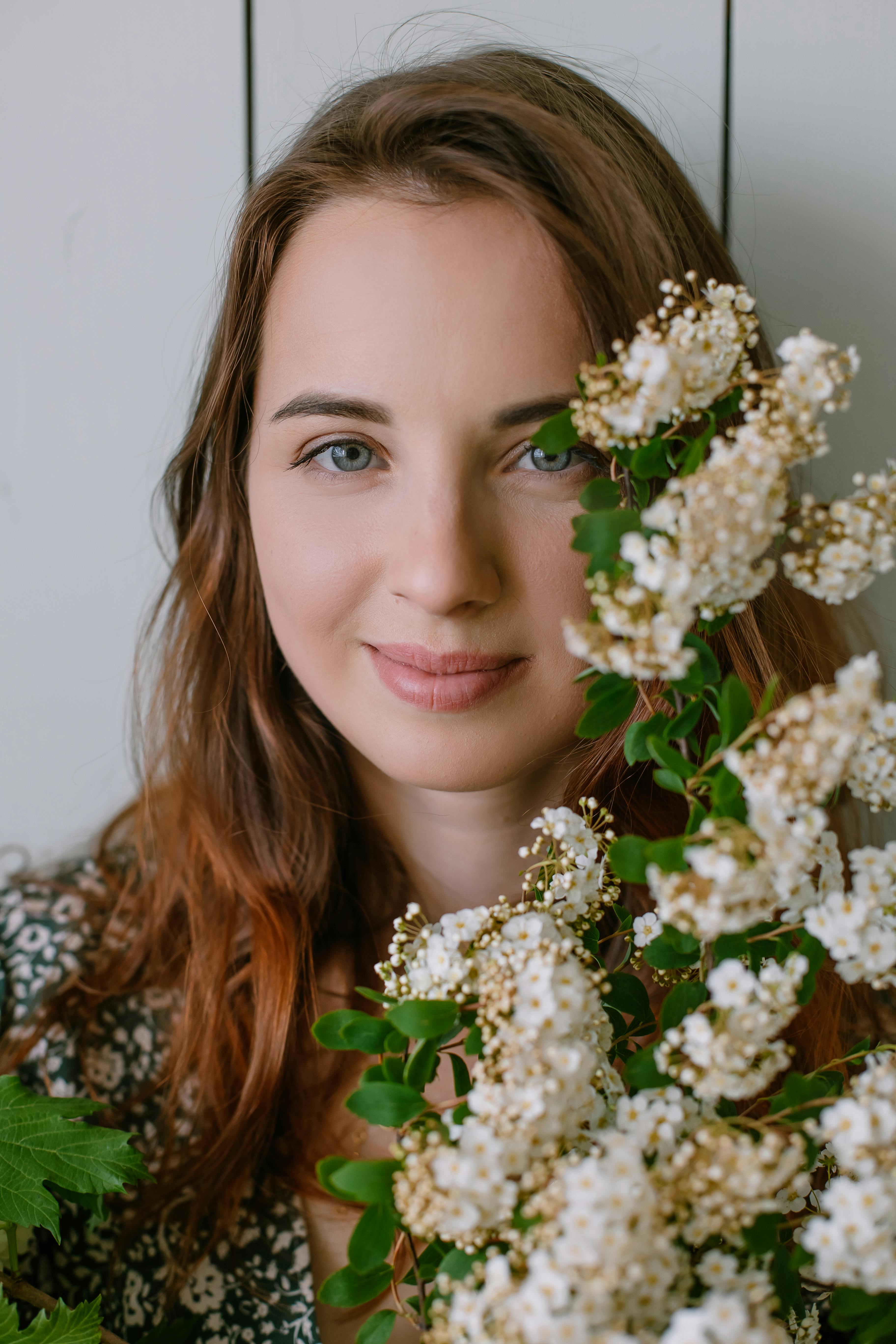 A young woman smiling with vibrant blossoms, capturing natural beauty.
