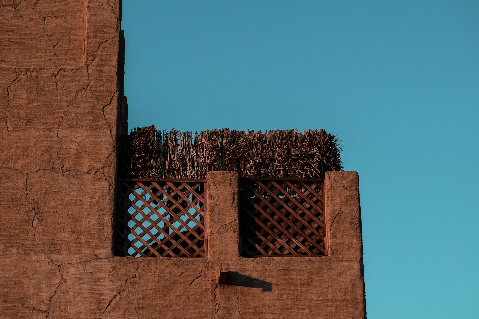 Rustic facade with a wooden lattice, captured under a clear blue sky in Dubai.