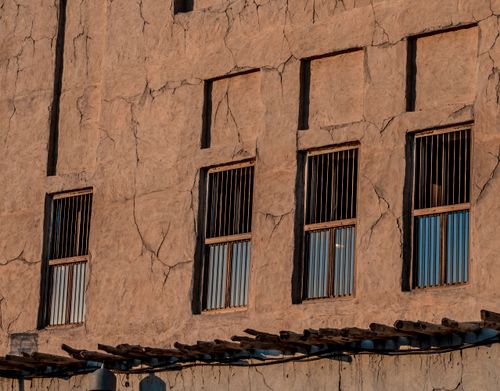 Free A detailed view of the weathered facade of a traditional building in Dubai, showcasing cracked walls and barred windows. Stock Photo