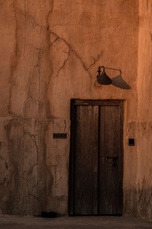 Free A weathered wooden door in a historic building facade in Dubai's Old Town, showcasing rich textures. Stock Photo