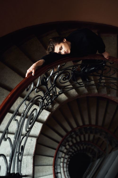 Free Atmospheric shot of a woman lying on an ornate spiral staircase bannister. Stock Photo