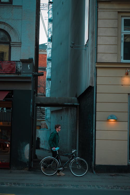 Young Man Walking with a Bicycle in a City 