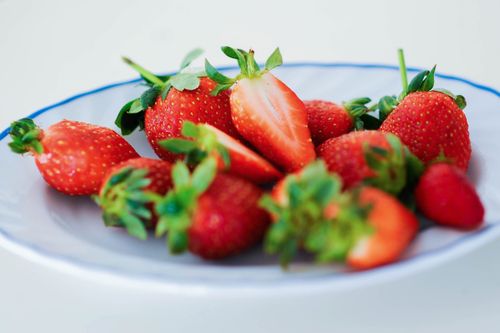 Free Close-up of fresh strawberries on a white plate with a blue rim. Stock Photo