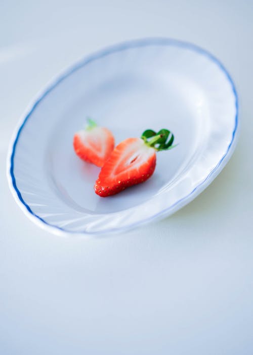 A Strawberry on White Ceramic Plate Sliced in Half