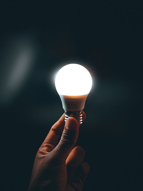 Close-up Photo of an Illuminated Light Bulb held by a Person 