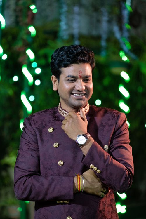 Free A cheerful man wearing traditional maroon clothing, illuminated by green lights outdoors. Stock Photo