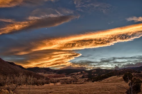 A Dramatic Sky with Yellow Clouds Over a Grassland Near Mountains