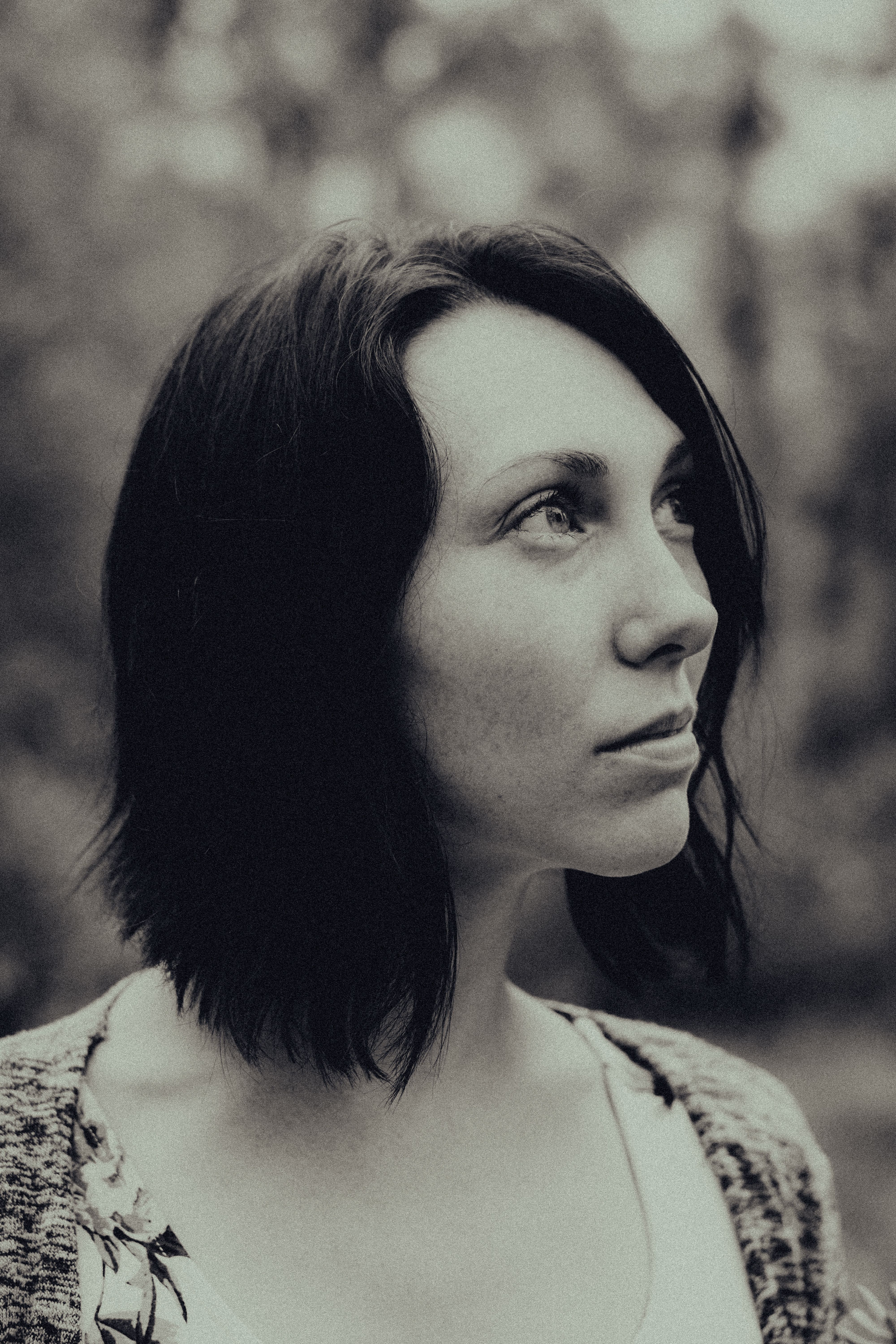 Elegant black and white portrait of a woman with short brunette hair outdoors.