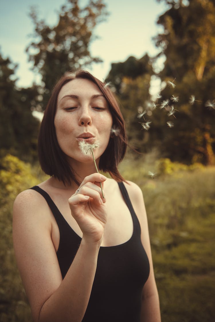 A Woman Blowing A Dandelion