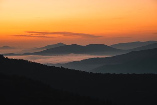 Free Breathtaking mountain silhouettes during a vibrant sunset. Stock Photo