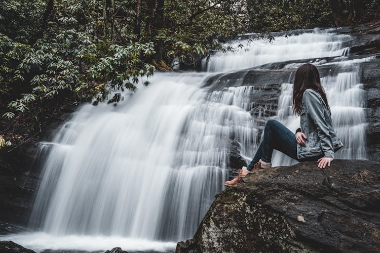 Woman Sitting Near Waterfall