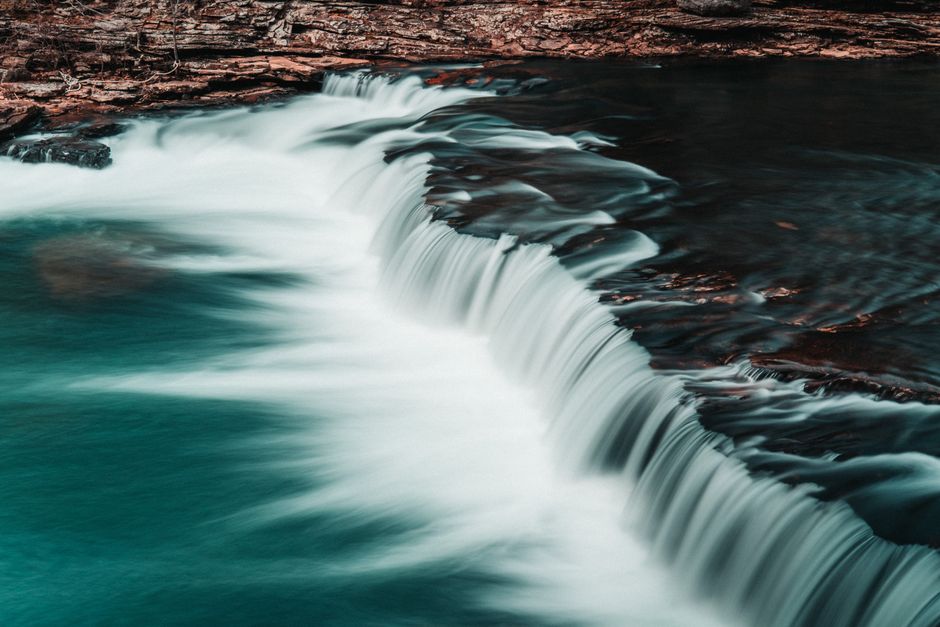 A tranquil cascade waterfall flowing over smooth rocks, captured in vibrant detail.