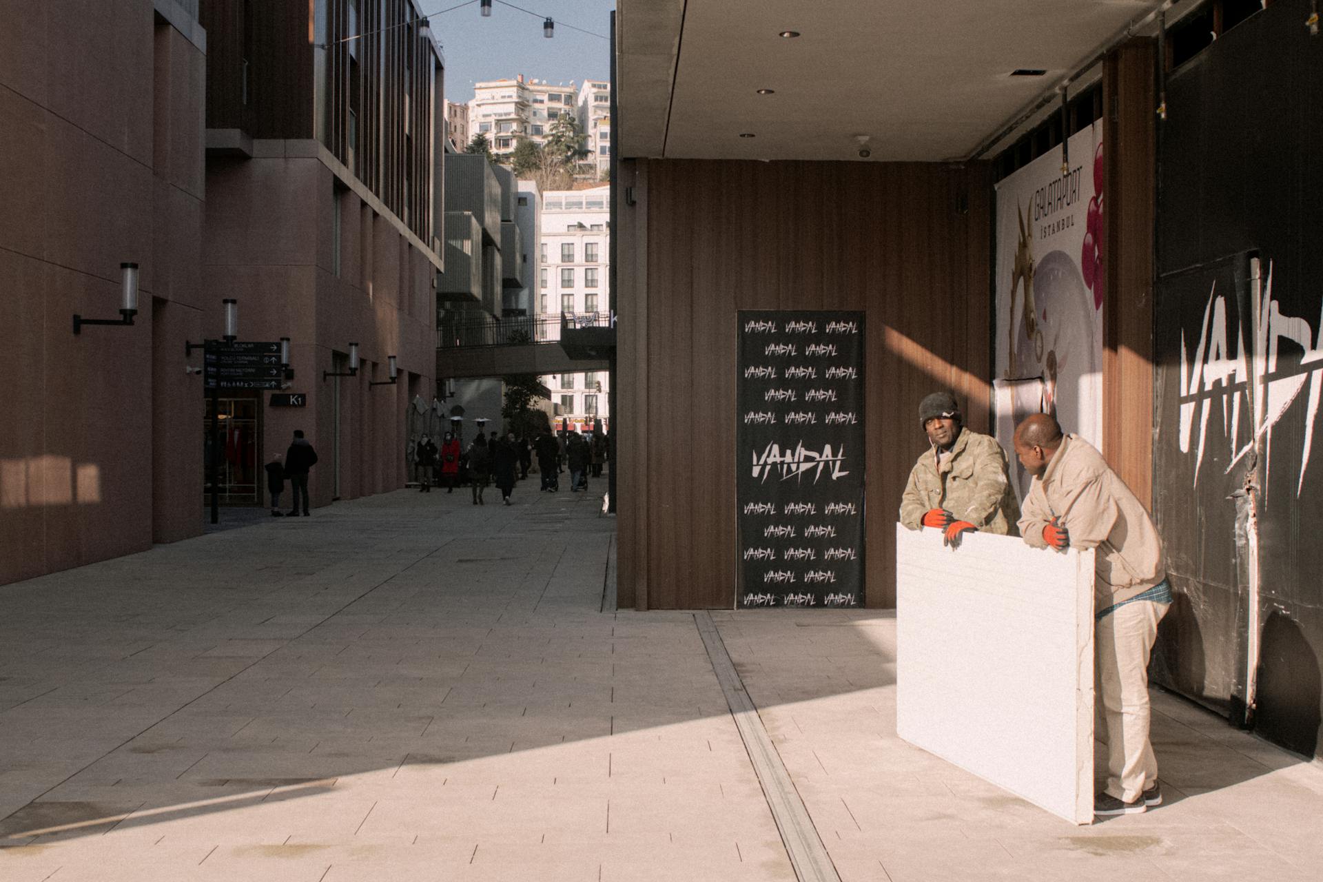 Busy street scene in Istanbul with two workers handling a large panel outdoors.