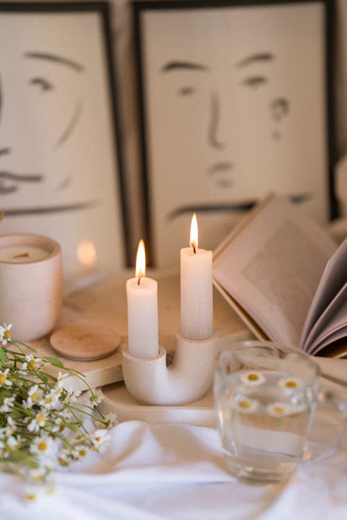 Free Table Arrangement of Lit Candles Book and Cut Wildflowers Stock Photo