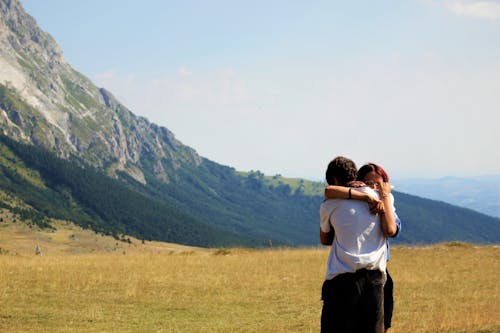 Free Back View of a Couple Hugging on the Grass Field Stock Photo