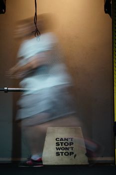 Long exposure capture of motion blur from an athlete running indoors, emphasizing determination with text 'Can't Stop Won't Stop'.