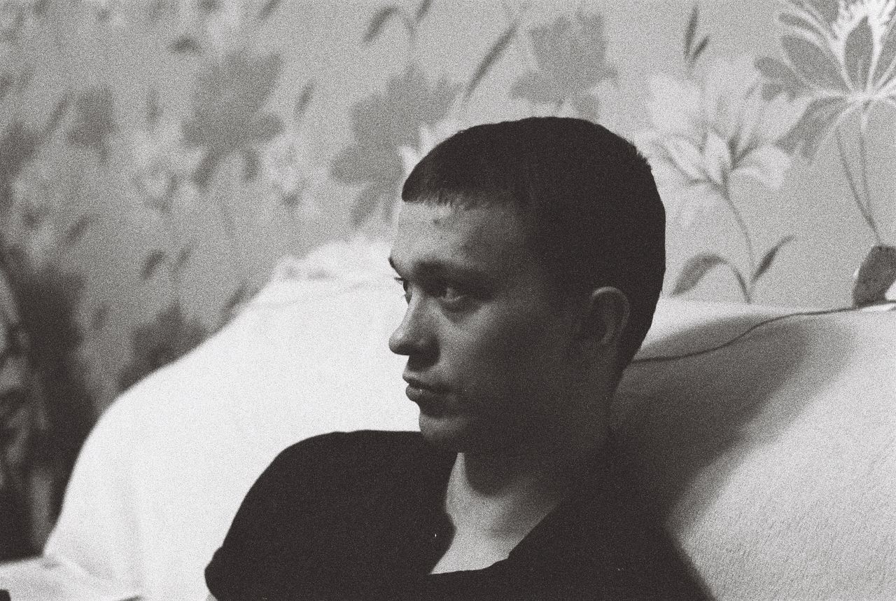 a man leans on a sofa deep in thought captured in striking black and w