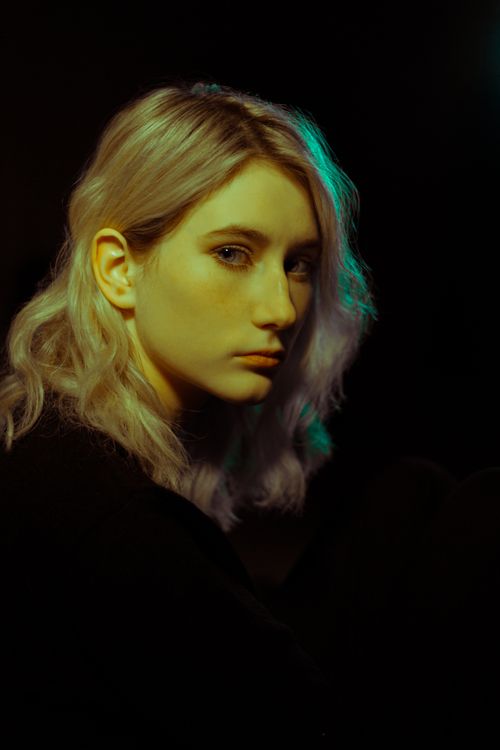 Free Low key portrait of a blonde woman against a dark background, capturing dramatic lighting. Stock Photo