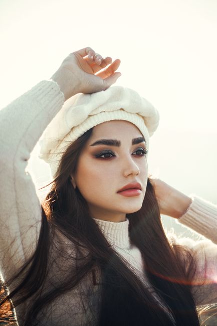 Stunning portrait of a woman in white sweater and beret with sunlight background.
