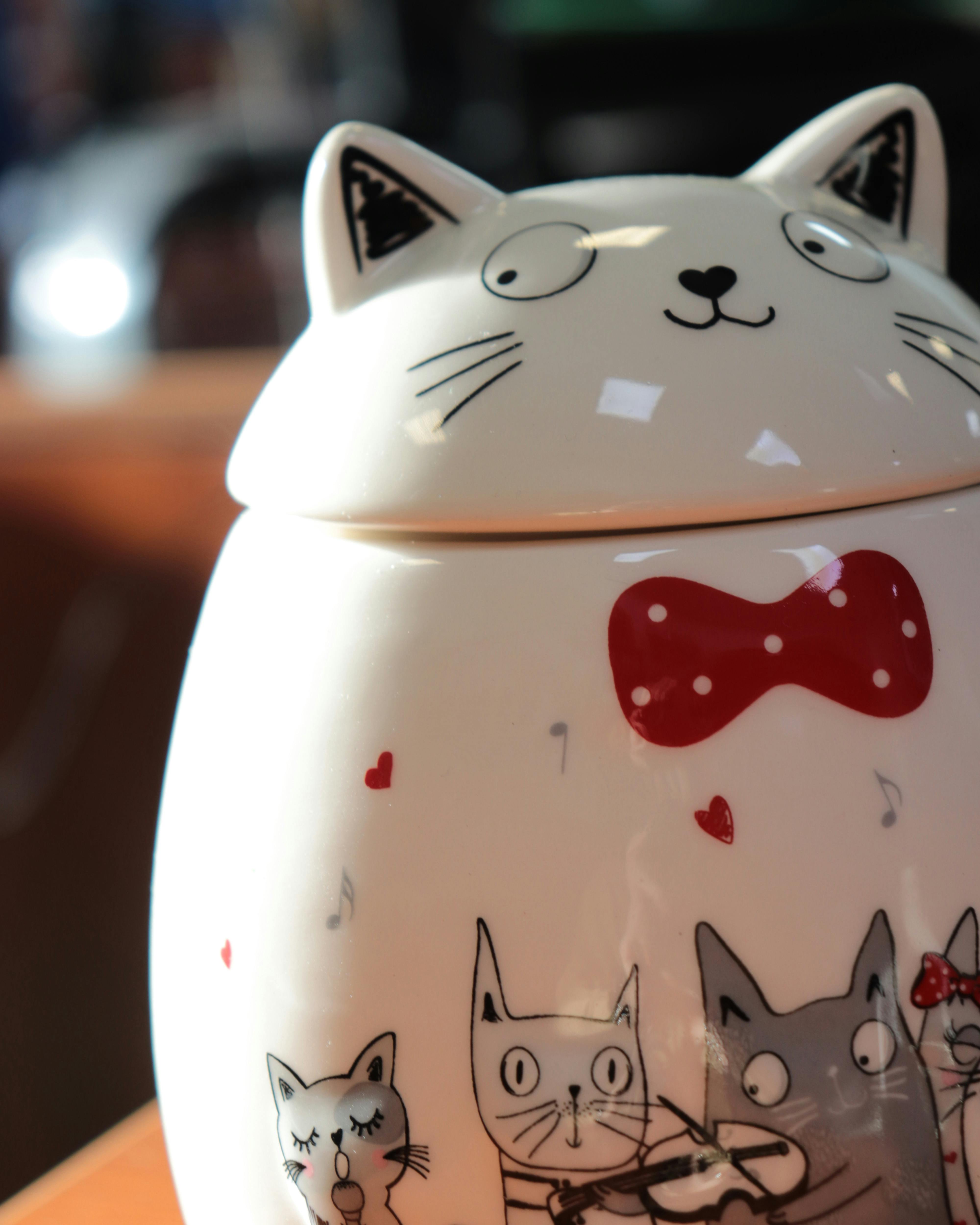 Close-up of a whimsical ceramic cat-shaped cookie jar with playful illustrations and vibrant colors.