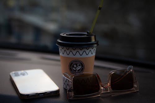 Close Up Photo of Disposable Cup near Sunglasses