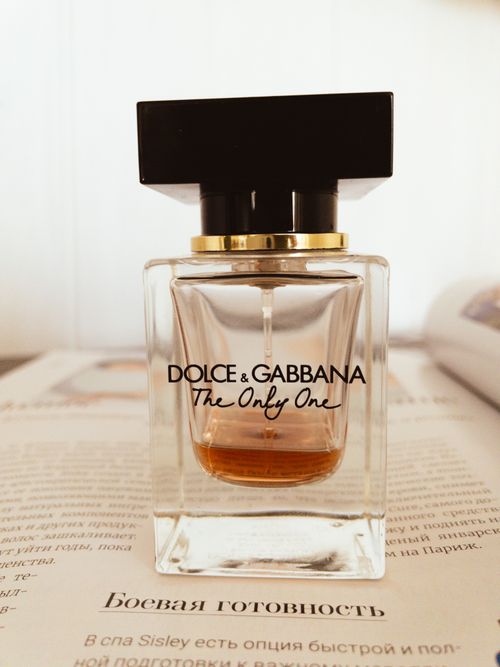 Free Elegant Dolce & Gabbana perfume bottle showcased on an open magazine with a neutral background. Stock Photo