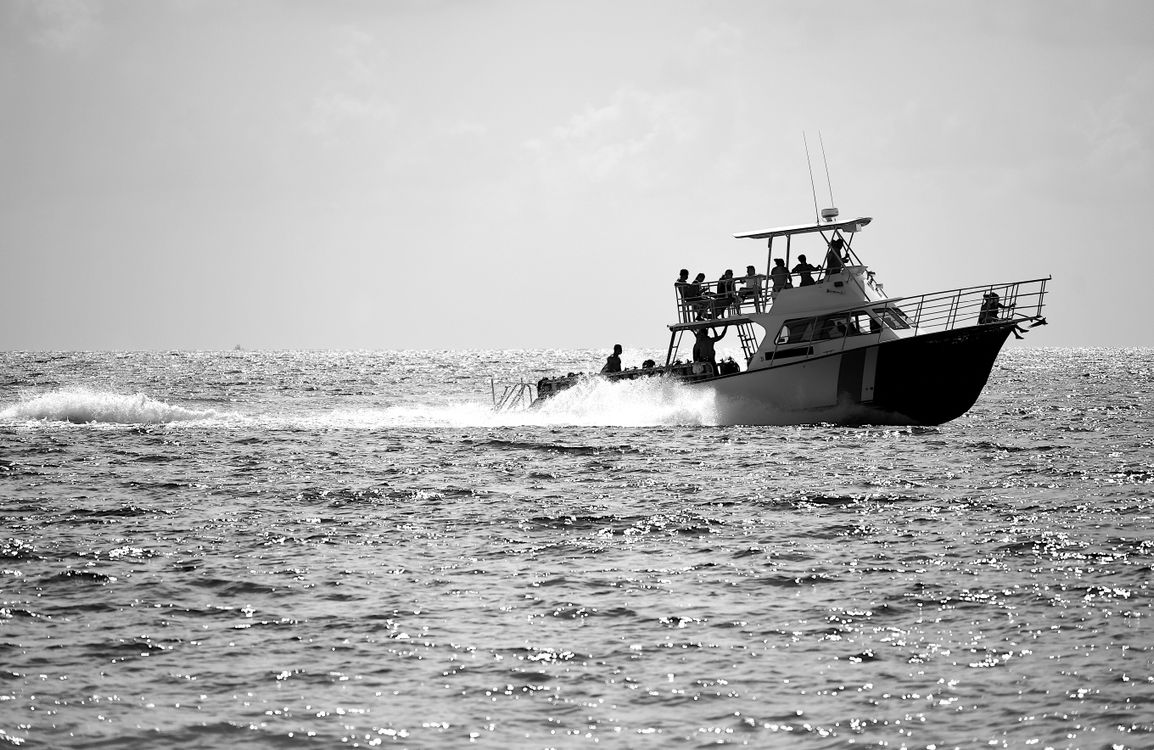 Grayscale Photo of People Riding on Boat on Sea · Free Stock Photo