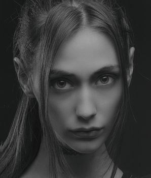 Close-up black and white portrait of a young woman with intense gaze.