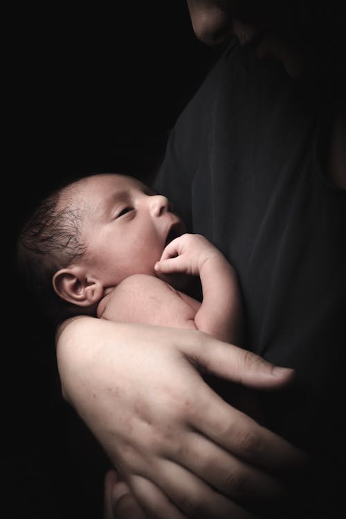 Free A Person in Black Shirt Carrying a Baby Stock Photo