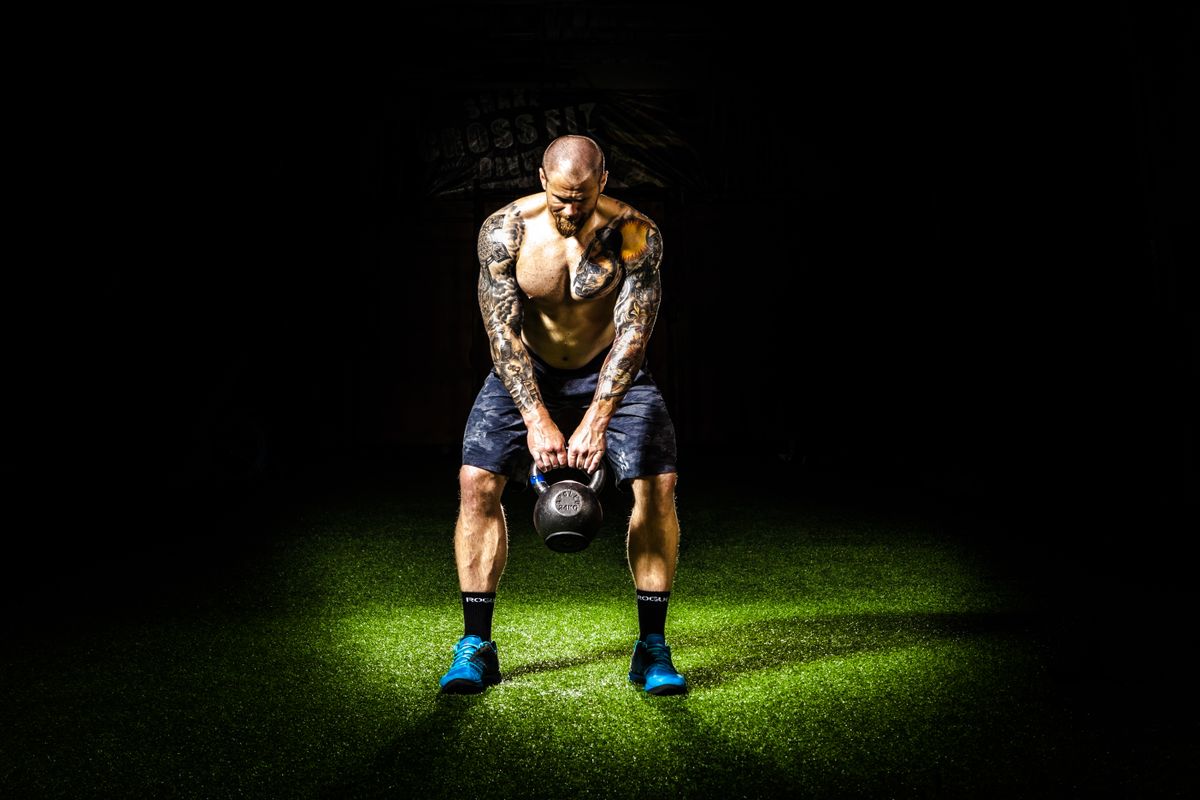 Man lifting a kettlebell during an intense workout, showcasing strength and explosive power