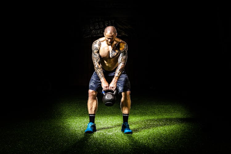 Man In Blue Shorts Carrying Brown Exercise Equipments