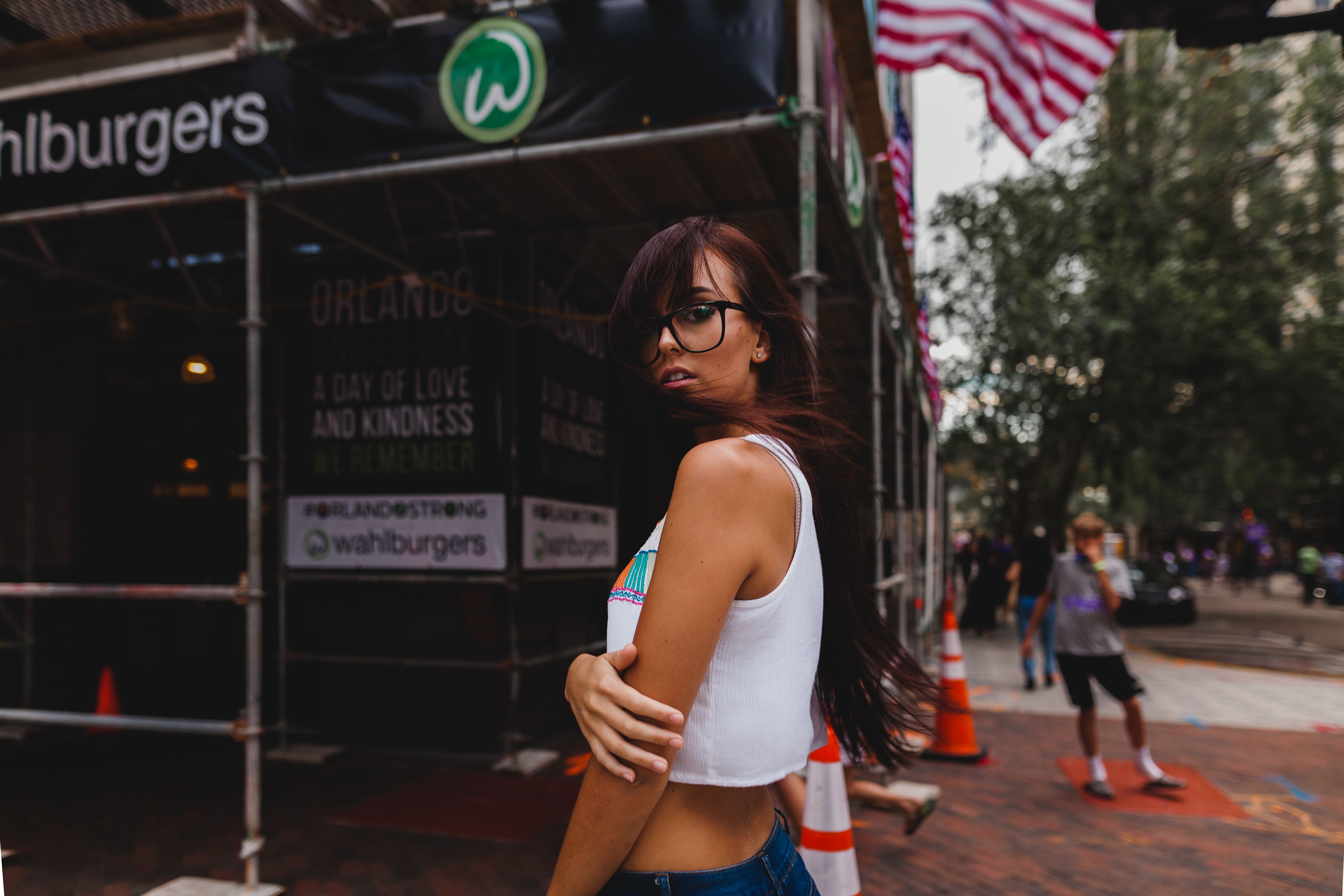 Woman in a white tank top on a sunny Orlando street with American flags
