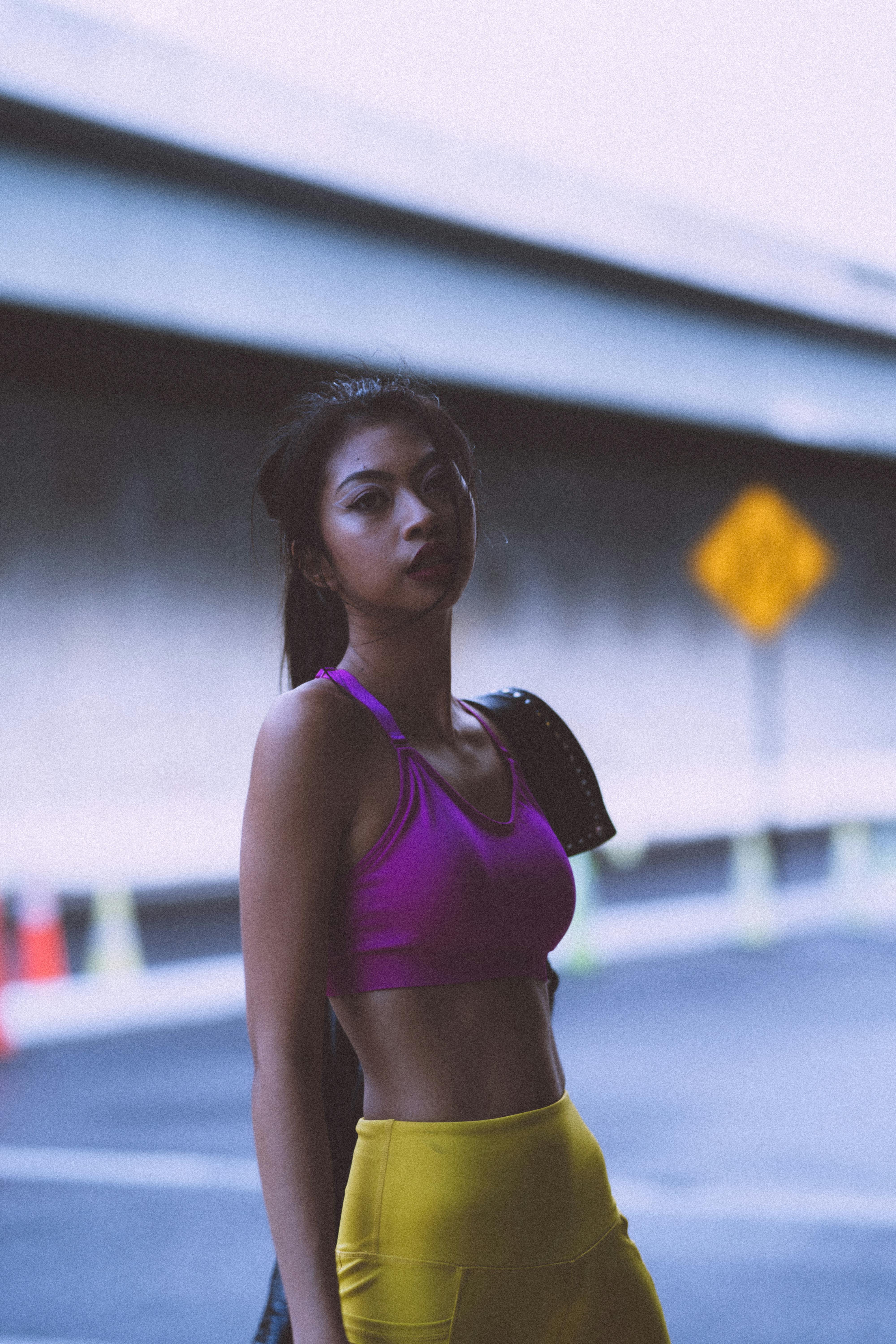 Portrait of a young woman in athletic wear under an urban overpass, radiating confidence and style.