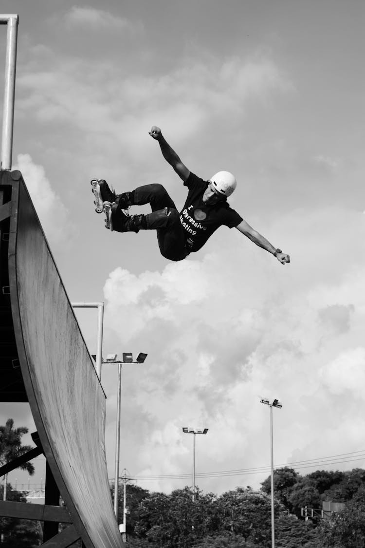 A Man Wearing Helmet And Roller Skates Doing A Stunt In The Air