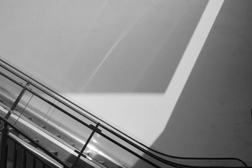 Free A striking minimalist photo of an escalator with geometric shadows in black and white. Stock Photo