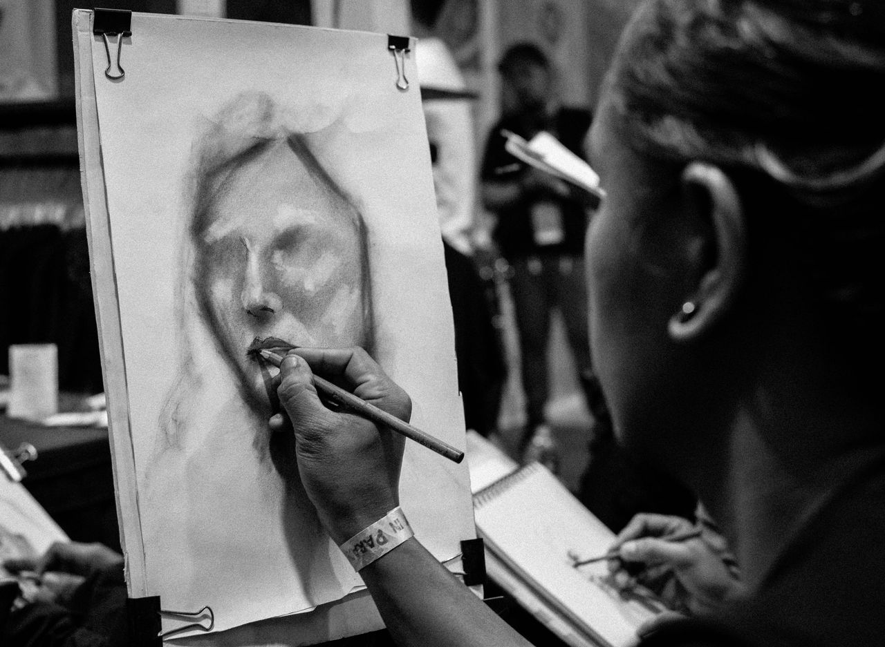 artist sketching a portrait in monochrome at an indoor workshop
