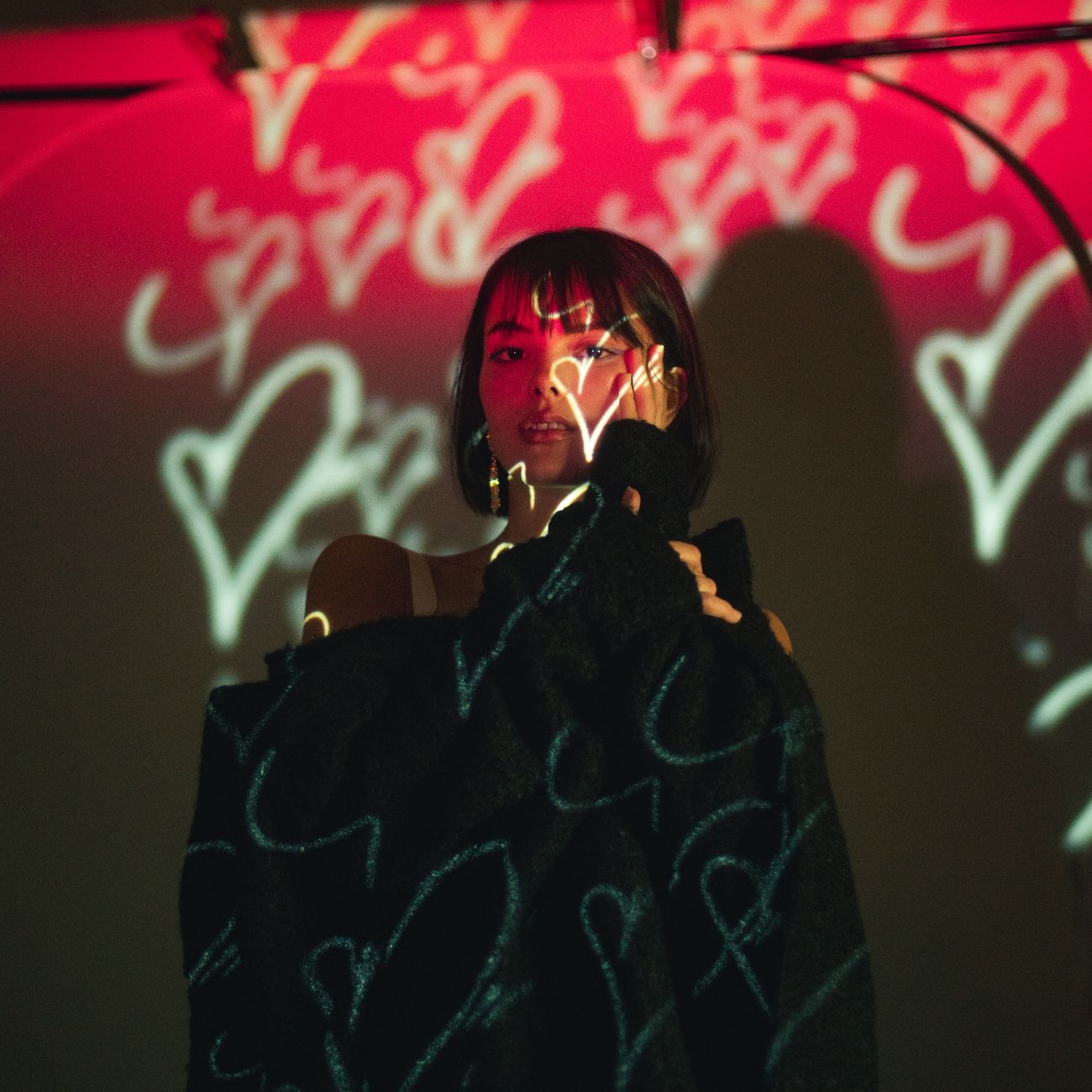 Young woman in a studio with creative heart-shaped light projections on her.
